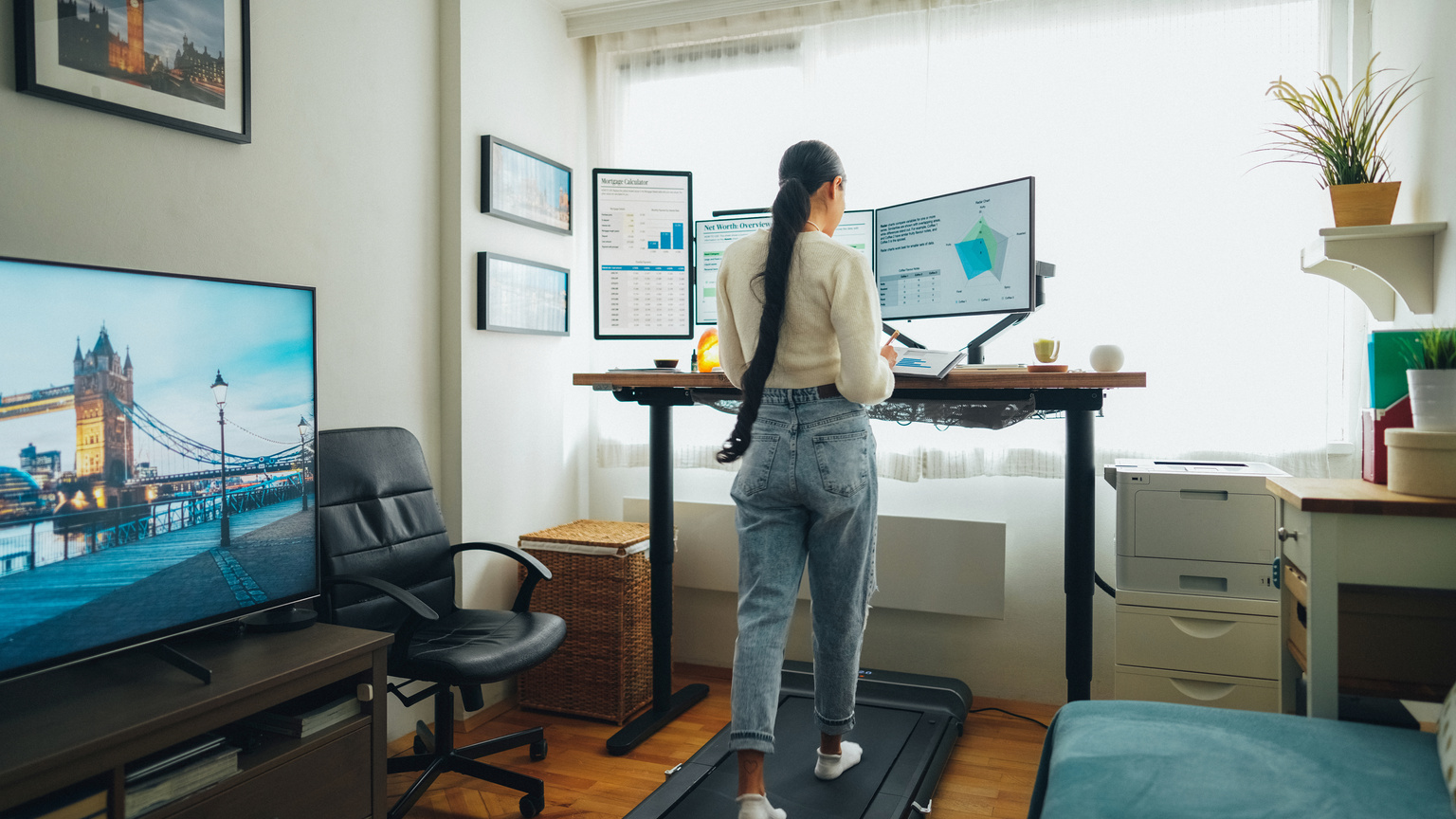 Woman at home office is walking on under desk treadmill